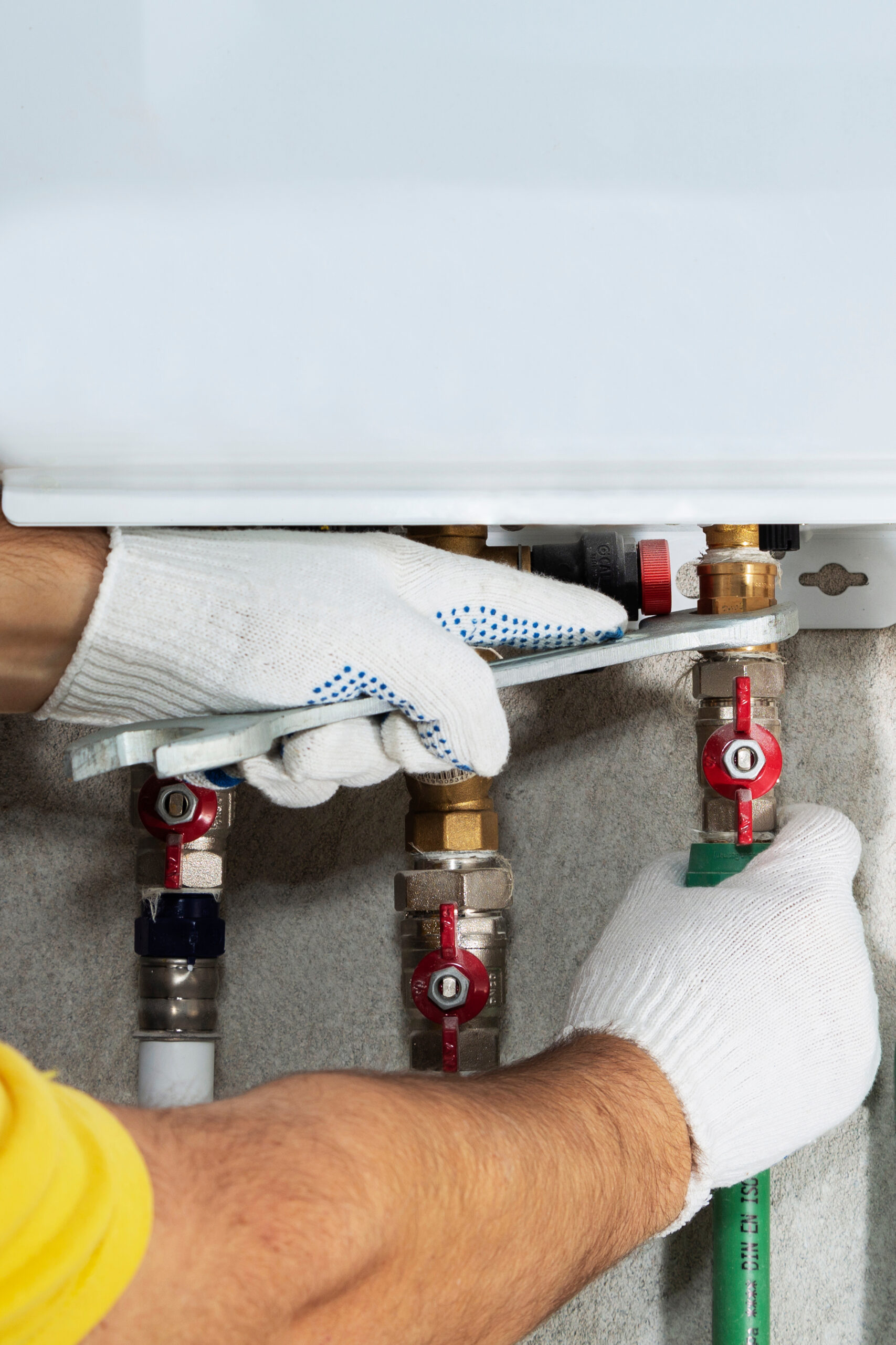 A plumber attaches to a gas pipe boiler with a wrench.